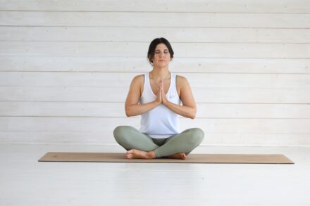 Woman meditating in a lotus pose on a mat.