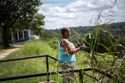 a woman holding a camera while standing next to a fence