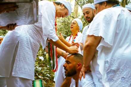 People in white clothing performing a ritual outdoors.