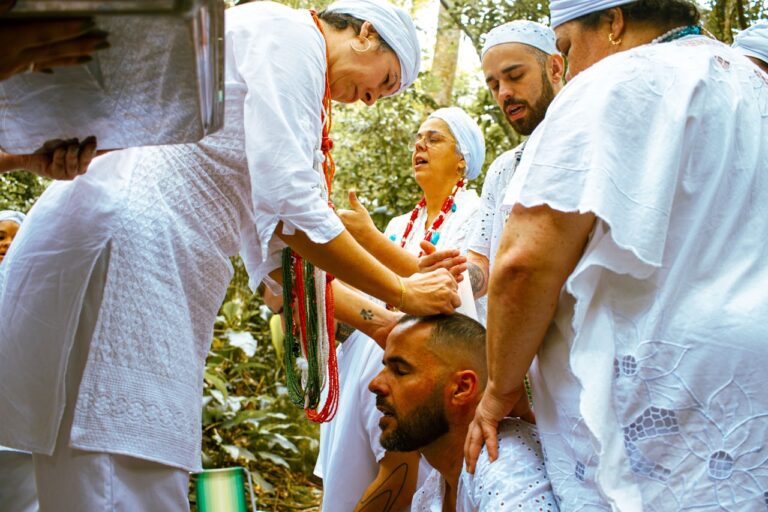 People in white clothing performing a ritual outdoors.