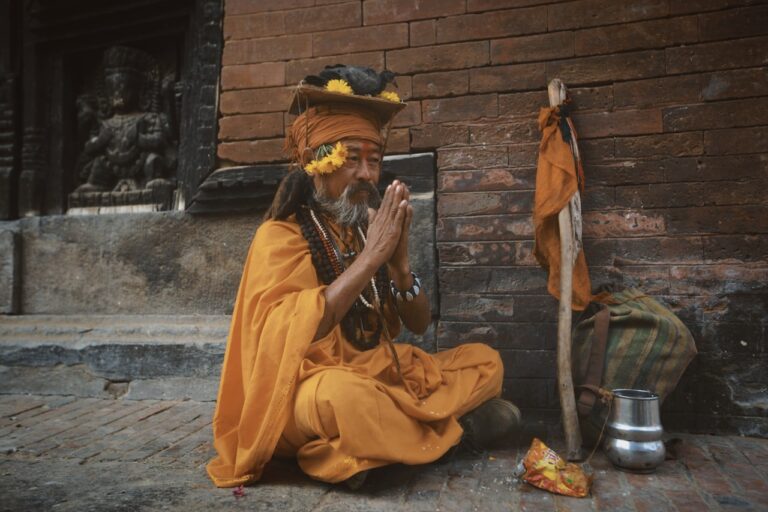 Traditional Healing Practices An elderly man in an orange robe prays outside.