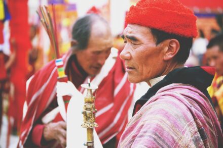 Man in red hat and traditional attire at festival.