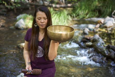 Energy Healing A woman in a purple dress holding a large bowl