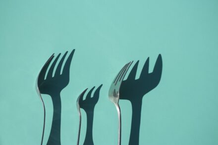 Energy Healing three gray metal forks casting shadow on green surface