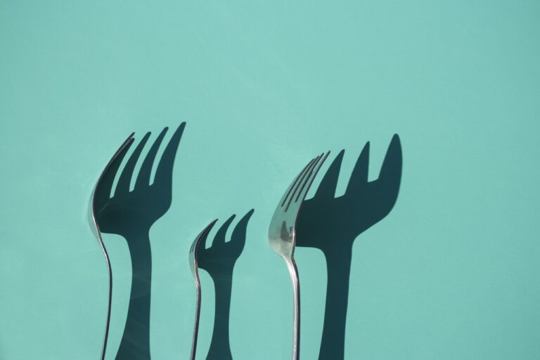 Energy Healing three gray metal forks casting shadow on green surface