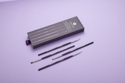 a set of five pencils and a box of pencils on a purple surface