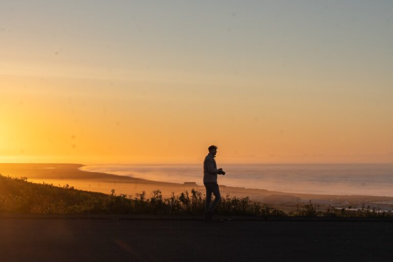 Yoga Man walking on a hill overlooking the ocean at sunset