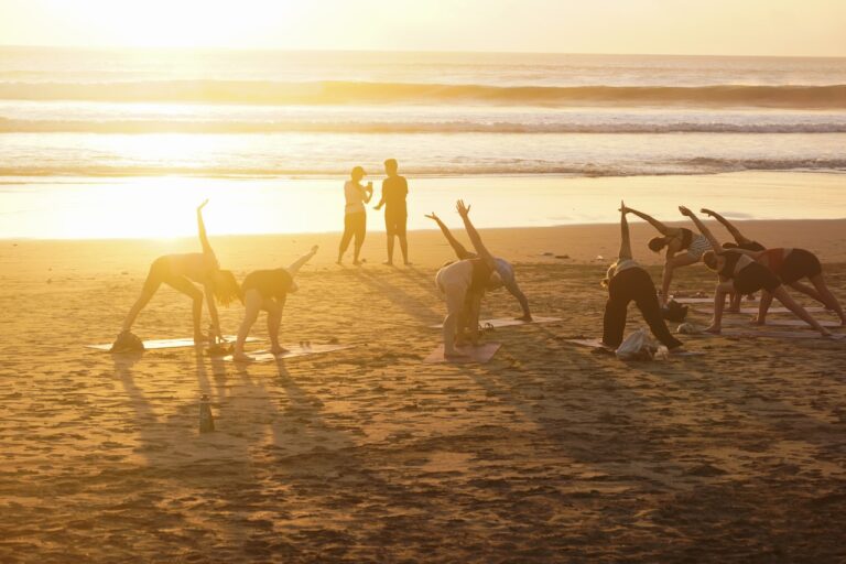 Yoga People practicing yoga on a beach at sunset.